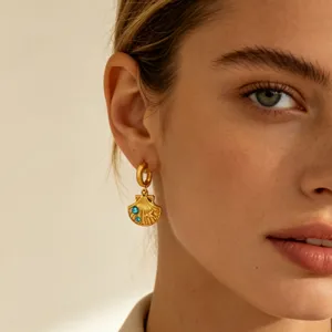 Gold shell ear pendant detail shot featuring sparkling blue stone inlay and elegant drop design.