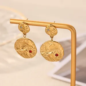 Close-up detail view of 18k gold plated textured drop earrings featuring red and blue crystal stones.