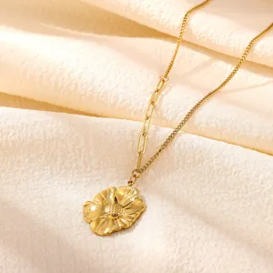 Detail view of a chic gold sunflower pendant necklace on textured fabric, elegant and minimalist.