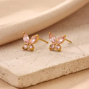 Detail shot of mini gold butterfly stud earrings with sparkling pink cubic zirconia on stone.