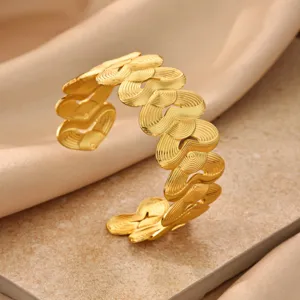 Close-up view of golden geometric pleated cuff bracelet showing fine metallic texture.