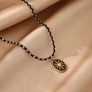 Close-up detail of the black and white braided rope chain with retro sun pendant charm.