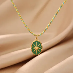 Close-up detail of a retro green enamel oval sun heart pendant with a braided cord necklace.