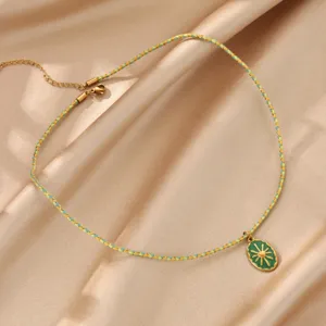 Close-up of the green sunburst pendant and braided colorful rope necklace detail shot.