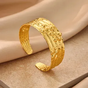 Gold textured metal cuff bracelet close-up, wrinkled geometric open bangle jewelry detail shot.