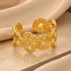 Detail shot of the gold-plated open cuff bracelet featuring unique swirling hollow geometric rings.