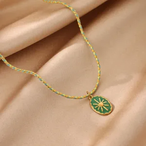 Closeup of the green enamel sun pendant necklace with a woven cord. Vintage jewelry detail view.
