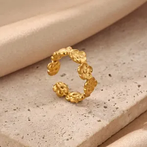 Close-up detail of gold flower stainless steel ring, elegant minimalist fashion jewelry design.