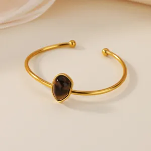 Closeup view of the gold-tone stainless steel cuff bracelet featuring a teardrop natural stone.