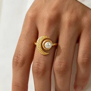 Close-up detail shot of a gold crescent moon ring featuring a delicate pearl center.