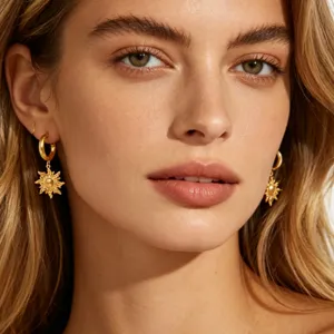 Detail close-up shot of gold sun pendant earrings, elegant and shiny fashion jewelry design.