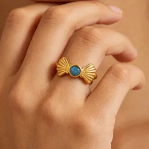 Close-up of a stylish gold-plated ring with a blue central stone, showcasing fine jewelry details.