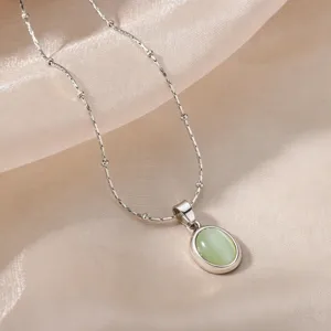 Minimalist silver titanium steel necklace with an oval green cat's eye stone pendant.