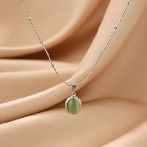 Detailed close-up view of oval green cat eye stone pendant and delicate beaded steel chain.