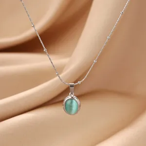 Close-up detail of an elegant oval green cat eye stone pendant necklace on silk fabric.