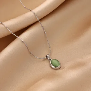 Close-up of elegant green cat's eye stone pendant necklace with delicate chain on soft fabric.