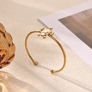 Detailed close-up of a stylish gold-plated stainless steel open turtle bracelet with white jade.
