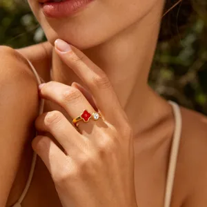 Detailed shot of gold plated stainless steel clover ring with red enamel and stone accent.