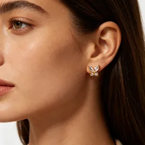 Close-up detail of dainty gold-plated butterfly stud earrings with sparkling cubic zirconia.