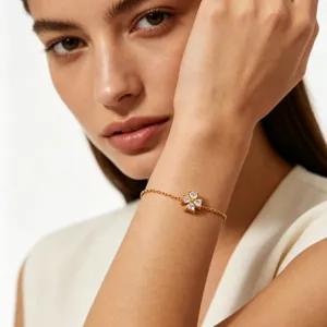 Closeup of a gold-plated stainless steel bracelet featuring a sparkly cubic zirconia clover charm.