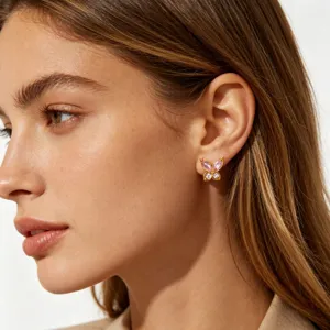 Close-up detail of exquisite gold plated pink zircon butterfly stud earrings on ear.