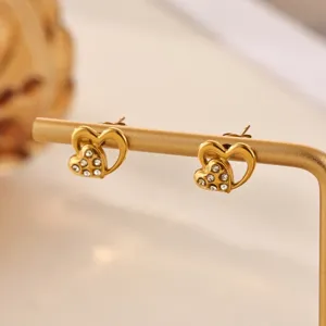 Close-up of elegant double heart gold stud earrings sparkling with clear crystal rhinestones.