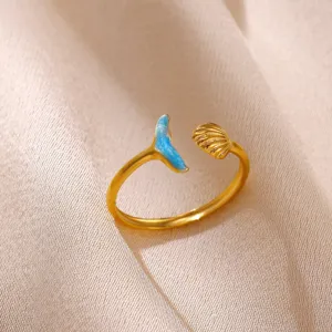 Gold plated open ring featuring a blue enamel whale tail and seashell design. Elegant jewelry.