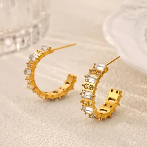 Close-up of gold rhinestone hoop earrings detail on textured background, elegant crystal jewelry.