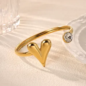Detailed shot of gold plated stainless steel open cuff bracelet with heart and crystal charm.