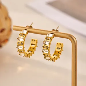 Close-up detail of stylish gold-toned hoop earrings adorned with sparkling crystal rhinestones.