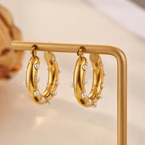 Close-up of elegant gold thick hoop earrings with pearl accents, stylish jewelry detail shot.