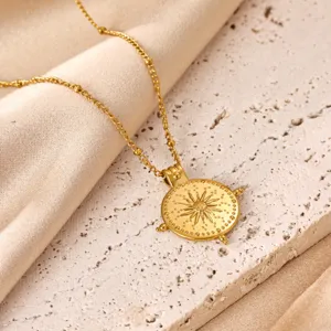 Close-up detail of the gold-plated compass pendant necklace, highlighting the sunburst engraving.