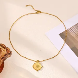Close-up detail of gold plated stainless steel sun compass pendant necklace with fine chain.
