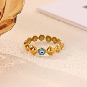 Detail view of 18k gold plated stainless steel beaded ring featuring a blue evil eye charm.