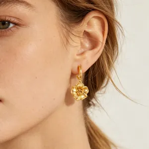 Gold flower huggie hoop earrings with delicate floral pendant design for elegant daily wear.
