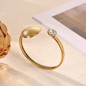 Gold-plated open cuff bracelet with textured shell motif and single sparkling crystal.