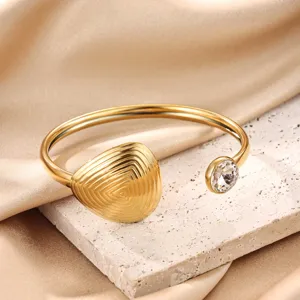 Gold plated cuff bracelet with sparkling rhinestone and textured drop detail close-up.