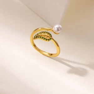 Detail close-up of gold open ring featuring green zircon leaf and elegant pearl decoration.
