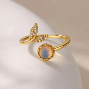 Close-up detail shot of a gold open ring featuring a leaf zircon design and a round opal stone.