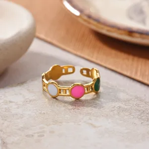 Stainless steel gold plated open ring close-up, featuring colorful enamel circles.