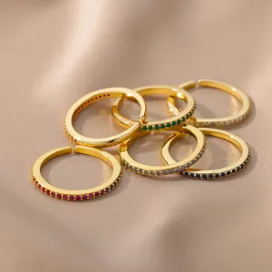 Close-up detail of stackable gold-plated rings featuring colorful paved cubic zirconia stones.