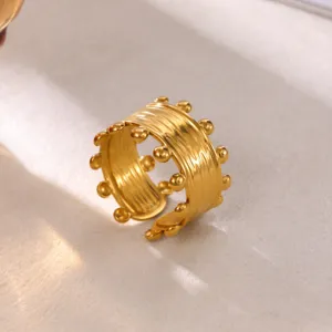 Close-up of gold plated stainless steel open ring with textured design and bead edges.