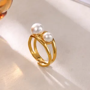 Detail view of minimalist 18K gold plated open ring with double white pearls on textured surface.