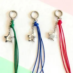 Star keychain detail close up, braided leather cord charm and metal star pendant accessory.