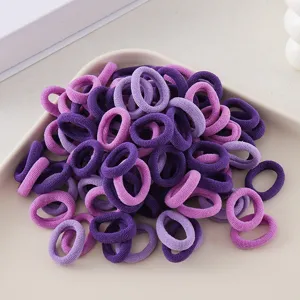 Close-up detail of seamless purple hair ties in a tray, soft elastic bands for girls styling.