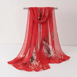 Vue détaillée d'un foulard en mousseline florale rouge vif, long châle de plage élégant.