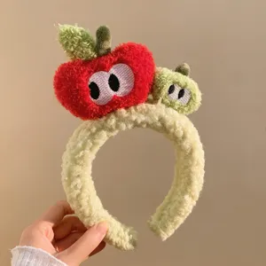 Plush apple headband detail showcasing soft textured fabric and cute embroidered eyes.
