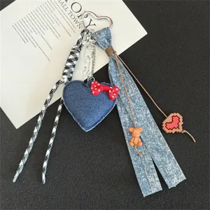 Close-up detail of the creative denim heart keychain with cute bear and red bow charms.