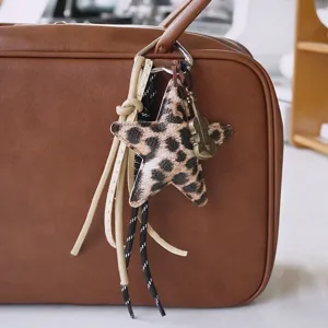 Gros plan détaillé du charm de sac étoile imprimé léopard avec pampilles et violon vintage.