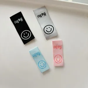 Primo piano dettagliato di etichette in tessuto intrecciato piegato colorato con smiley e ricamo.